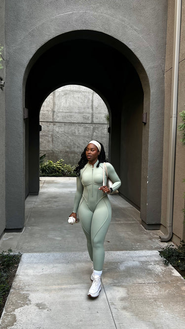 Woman in a green athletic outfit walking through an archway.